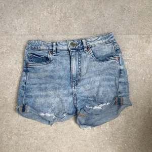 Ljusblå jeansshorts från LAB Industries - Snygga ljusblå jeansshorts från LAB Industries med upprullade och slitna benslut. Klassisk femficksmodell, bälteshällor och dragkedja. Perfekta för varma dagar och ger en avslappnad vibe.