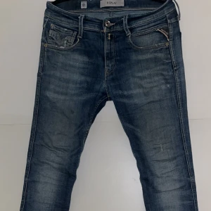 Blå Replay jeans med slitningar - Blå jeans från Replay med femficksdesign och slitna detaljer. Jeansen är köpta för 1200kr. Jeansen har en defekt, därför säljer jag för 539kr