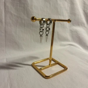 Silvriga örhängen med kedjor och spikes - Coola silvriga örhängen med två kedjelänkar och spetsiga spikes längst ner. De har en modern och edgy vibe, perfekta för att lyfta din stil. Örhängena är i metall och har en minimalistisk men ändå tuff design.