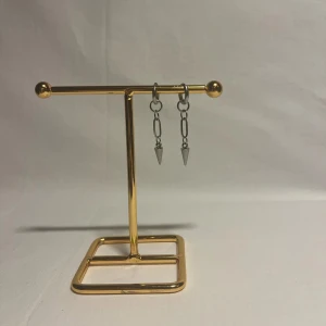 Silvriga örhängen med kedja och spike - Ett par coola silvriga örhängen med små hoops, kedjor och spetsiga spike-detaljer längst ner. Ger en edgy vibe och passar perfekt för dig som gillar att sticka ut med din stil.
