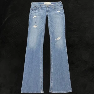 Jeans från Hollister ljusblå - Ljusblå jeans från Hollister med slitna detaljer och klassisk femficksdesign. Jeansen har låg midja och är tillverkade i mjuk bomullsdenim med snygg tvätt och slitningar framtill. Perfekta för en avslappnad och trendig look. Dem passar inte mig så har inga bilder med dem på. 