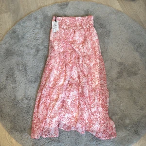 Rosa paisleymönstrad långkjol - Supersnygg långkjol i rosa och vitt med paisleymönster och smock i midjan. Aldrig andvänd 