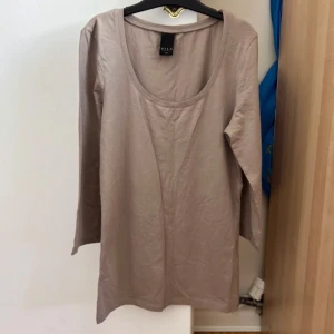 Beige långärmad tröja från Vila - En basic beige långärmad tröja från Vila med rund halsringning. Tröjan är i mjuk bomull och har en enkel, clean design som passar perfekt till jeans eller kjol. Modellen är normal i passformen och har långa ärmar.