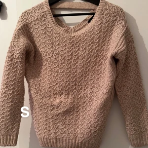 Beige stickad tröja med strukturmönster - Beige stickad tröja med snyggt strukturmönster och rund halsringning. Tröjan har långa ärmar och ribbade muddar vid ärmslut och nederkant. Perfekt för lager-på-lager och passar till både jeans och kjol.🌸Fint använt skick. Storlek s