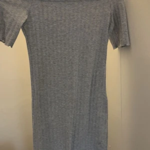 Grå kortärmad t-shirtklännings - En enkel och stilren grå t-shirtklänning med korta ärmar och rak passform. Perfekt för en avslappnad look och lätt att matcha med sneakers eller sandaler.