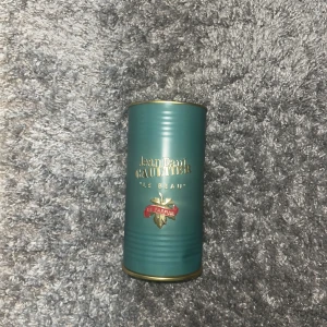 Jean Paul Gaultier Le Beau Le Parfum 75ml - Jean Paul Gaultier Le Beau Le Parfum i 75ml flaska. Parfymen kommer i en snygg turkos metallburk med gulddetaljer. Flaskan har en unik design i form av en manlig torso i mörkgrönt glas med guldfärgad spraytopp och står på en röd sammetsbas.