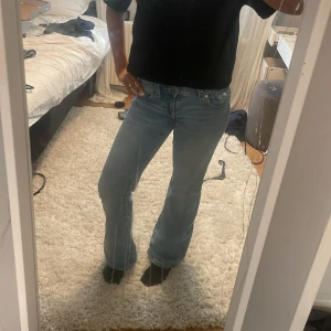 Ljusblå bootcut jeans - Säljer ett par ljusblå jeans med bootcut passform och klassisk femficksdesign. Jeansen har låg midja och är tillverkade i mjukt denimtyg. Perfekta för dig som gillar en avslappnad men ändå snygg stil.