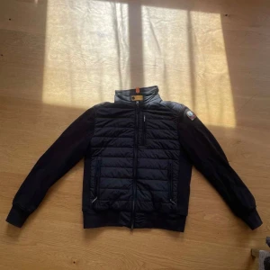 Svart quiltad jacka från Parajumpers - Snygg svart jacka från Parajumpers med quiltad front och rygg, samt mjuka ärmar. Jackan har hög krage, dragkedja framtill och coolt PJS-märke på ena ärmen. Perfekt för dig som vill ha en stilren och sportig look. Köpt på Urban på väla för 7000 kr. 