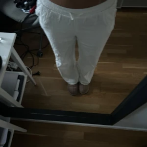 Vita linnebyxor med resårmidja - Säljer ett par vita linnebyxor med avslappnad passform och resår i midjan. Byxorna har raka ben och sidfickor, perfekta för en chill och luftig stil. Superbekväma och lätta att matcha med allt.