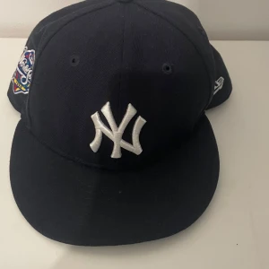 New Era Yankees 59FIFTY keps svart - Snygg svart New Era 59FIFTY keps med New York Yankees broderad logga framtill och World Series patch på sidan. Klassisk rak skärm med grön undersida och broderade detaljer. Perfekt för dig som gillar streetwear och sportig stil.