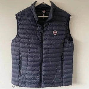 Mörkblå dunväst från Colmar - Snygg mörkblå dunväst från Colmar med quiltad design och dragkedja framtill. Västen har två fickor med dragkedja och justerbar dragsko nedtill. Colmar-logga på bröstet ger en sportig vibe💫SJÄLVKLART ÄKTA!