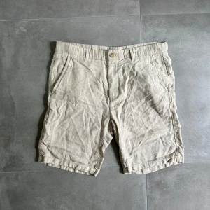 Beige linneshorts från Zara - Snygga beige shorts från Zara i en mix av linne och bomull. De har klassisk passform, bälteshällor, sidofickor och bakfickor med knapp. Perfekta för varma dagar när du vill ha en chill och stilren look. Artnr: C385