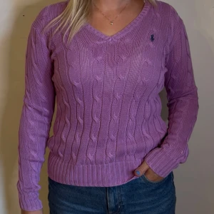 Rosa Ralph Lauren V-ringad kabelstickad damtröja  - En jättefin rosa v-ringad kabelstickad tröja från Ralph Lauren | storlek S | tillverkad i Pima cotton vilket gör att materialet är superskönt och stretchigt | skick 10/10 använd några gånger bara | skriv vid frågor!