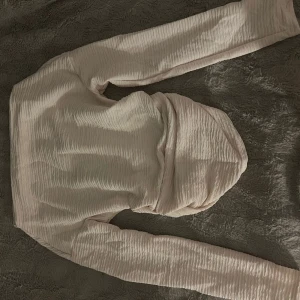 Ljusbeige hoodie med struktur - Säljer en ljusbeige hoodie med lång ärm och snyggt strukturerat tyg. Tröjan har huva och är tillverkad i ett lätt, vågigt material som ger en cool och modern look. Perfekt för dig som gillar stilrena och bekväma plagg.