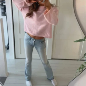 Ljusblå bootcut jeans med fickdetaljer - Säljer ett par ljusblå jeans med bootcut passform och snygga fickdetaljer med knappar bak. Jeansen har låg midja och är tillverkade i klassiskt denimtyg. Perfekta för dig som gillar en avslappnad men trendig look. Stl 170, men har tagit ner sömmen så de är lite längre.