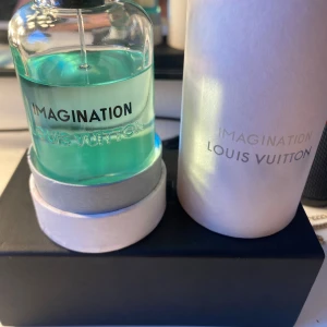 Louis Vuitton Imagination parfym - Lyxig parfym från Louis Vuitton, Imagination, i en stilren glasflaska med turkosblå vätska. Flaskan har svart lock med LV-logga och kommer med original vit förpackning. Perfekt för dig som vill ha en exklusiv doft i snygg design.