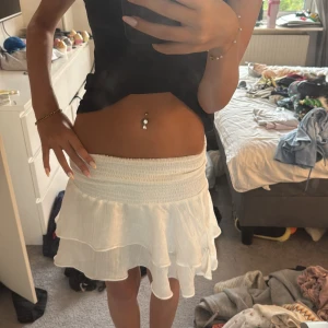 Vit volangkjol - Supersöt vit kortkjol med dubbla volanger. Kjolen är luftig och lätt, perfekt för varma dagar. Den har en flowy känsla och sitter bekvämt på höften. Enkel att matcha med crop tops eller linnen för en fräsch look. 💓