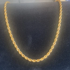 Guldfärgat tvinnat halsband - Snyggt halsband i guldfärg med tvinnad kedja i nytt skick, kedjan är inte i riktigt guld men är gjord av stål, 50cm lång, 75kr