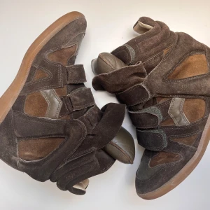 Bruna Isabel Marant wedge sneakers - Snygga wedge sneakers från Isabel Marant i olika bruna nyanser av mocka och skinn. Skorna har tre kardborreband, rund tå och platt gummisula. 