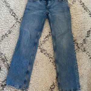 Lågmidjade blåa straight jeans från Gina Tricot - Klassiska blå jeans från Gina tricot med rak passform och låg midja. Jeansen har fem fickor, dragkedja och knapp framtill. Tillverkade i slitstarkt denimtyg som ger en tidlös look. Perfekta för dig som gillar enkel och clean stil.