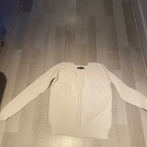 Vit stickad tröja från Pahladium - Säljer en vit stickad tröja från Pahladium i storlek 38. Tröjan är tillverkad i 100% bomull och har ett snyggt, grovt stickat mönster. Rund halsringning och långa ärmar gör den perfekt för kyligare dagar. Enkel och stilren design som passar till det mesta.