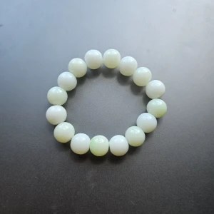 Vitt pärlarmband med stora pärlor - Stilrent armband med stora, runda vita pärlor trädda på elastisk tråd. Perfekt accessoar för att ge din outfit en clean och fräsch touch. Passar dig som gillar minimalistiska smycken med en klassisk vibe. Liten I storleken 