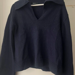 Mörkblå stickad tröja Gina Tricot - Mysig mörkblå stickad tröja från Gina Tricot med v-ringning och krage. Tröjan har långa ärmar, ribbade muddar och slits i sidorna.🧡
