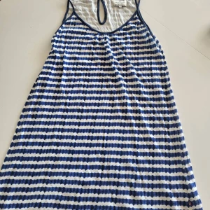 Randig sommarklänning från Lexington - Snygg ärmlös kortklänning från Lexington i blått och vitt med randigt mönster. Klänningen har en avslappnad passform och rund hals med en liten öppning bak. Perfekt för varma dagar och enkel att styla med sneakers eller sandaler.