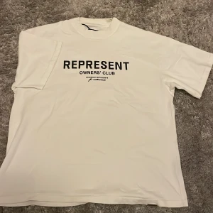 Vit Represent t-shirt Owners' Club - Vit t-shirt från Represent med svart tryck 'REPRESENT OWNERS' CLUB' på bröstet. Passform: Oversized. 