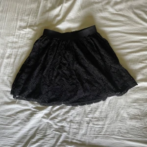 Svart spetskjol från Cubus - Supersöt svart kortkjol från Cubus med bred resår i midjan och vacker spets över hela kjolen. Passar väldigt bra nu till sommaren, och den är i storlek M. Säljs för att den inte kommer till användning. Fråga på!