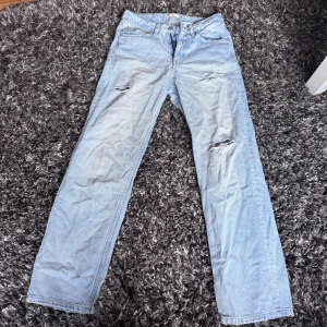 Ljusblå raka jeans från Gina Tricot - Ljusblå jeans från Gina Tricot med raka ben och slitna detaljer på låren. Klassisk femficksmodell med justerbar midja på insidan. Jeansen har en avslappnad vibe och är tillverkade i bomullstyg.