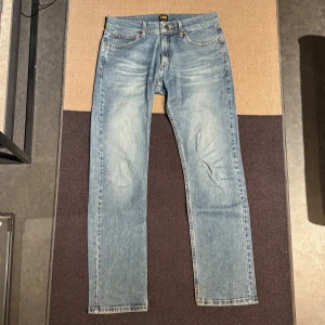 Ljusblå jeans från Lee - Snygga ljusblå jeans från Lee med klassisk femficksdesign och raka ben. Jeansen har Lee-logga på bakfickan och är tillverkade i mjukt denimtyg. Perfekta för en avslappnad och stilren look. Strl 31/32
