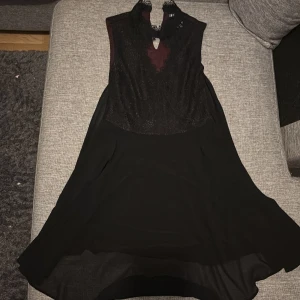 Svart spetsklänning från NLY Trend - Världens finaste klänning/se sista bilden, saknas en liten sån man sätter ihop knappen med en sådan metallbit, ena sidan hel på ryggen saknas den lilla delen som är som err litet knäppe.därav priset inköp 1499, går med synål och tråd eller med vanlig säkerhetsnål.  svart kortklänning från NLY Trend med spets upptill och ärmlös design. Klänningen har hög hals med liten öppning fram och lätt utställd kjol. Perfekt för dig som vill ha en elegant och stilren look med extra detalj i spetsen.