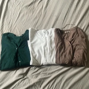 3-pack koftor i grönt, vitt och brunt - Säljer tre stilrena koftor i olika färger: en djupgrön, en klassiskt vit och en mjuk brun. Alla har knappar framtill, lång ärm och är i tunt, skönt material. Perfekta att slänga över en t-shirt eller linne för en chill look.