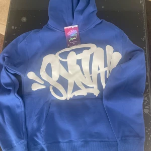 Syna World Hoodie blå - Hej! Säljer en Syna Hoodie i färgerna blå och vit. Tröjan är i storlek Medium. Den har även inga slitningar. Pris: 600kr.