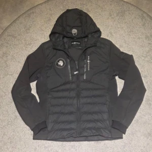 En svart Sail Racing jacka  - En jacka som är perfekt för hösten och våren och även när det är lite kyligt. De passar till mycket och är en jacka som är ganska unik på sitt sätt. Det finns inga skador eller skar märken, har haft den ungefär 1 år.