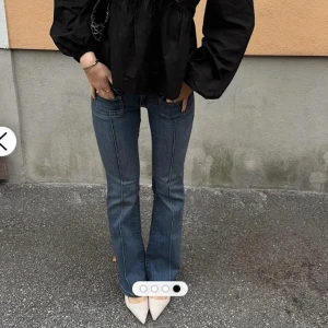 Blå bootcut jeans med fickor - Snygga blå jeans med bootcut-modell och markerade sömmar framtill. Byxorna har stora fickor fram och en klassisk jeanslook. Perfekta för dig som gillar en retrovibe och vill ha ett par jeans som sticker ut lite extra.