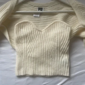 Vit ribbad bolerotopp från SHEIN - Superfin vit ribbad bolerotopp från SHEIN med croppad passform och långärmade ärmar. Toppen har en snygg sweetheart-urringning och är stickad i mjukt material. Perfekt att styla över linne eller klänning för en trendig look.