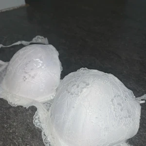 Vit spets-bh från Censored 80D - Säljer en vit bh push up bh i storlek 80D. Bh:n har vacker spets över kuporna och längs axelbanden, samt små rosetter framtill. 