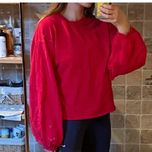 Röd oversized sweatshirt med ballongärm - Röd oversized sweatshirt med ballongärmar och rund hals. Tröjan har en avslappnad passform och är perfekt för dig som gillar en chill och trendig stil. Tillverkad i mjuk bomull som känns skön mot huden.