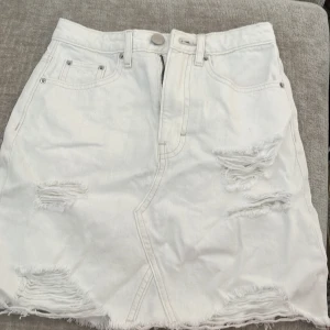 Vit jeanskjol från H&M Divided - Vit jeanskjol från H&M Divided med slitna detaljer och fransad nederkant. I storlek 32💓