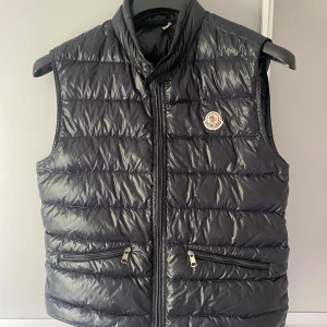 väst från Moncler äkta! - Snygg svart dunväst från Moncler med glansig finish och klassisk logga på bröstet. Skriv om frågor eller mer bilder. 