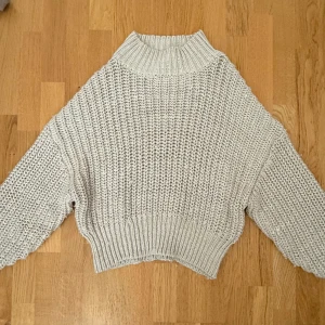 Beige stickad tröja från H&M - Supermysig beige stickad tröja från H&M med grovstickat mönster och hög krage. Tröjan har en loose passform och långa ärmar, perfekt för lager på lager. Passar dig som gillar en chill och avslappnad stil.