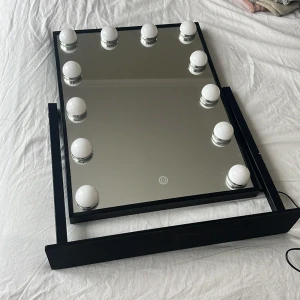 Sminkspegel med LED-lampor - Snygg sminkspegel med svart ram och 10 stora LED-lampor runt spegeln. Touchknapp på spegeln för att tända och släcka belysningen. Spegeln står stadigt på ett svart ställ och drivs med medföljande strömadapter. Säljer den för att vi har flyttat och den får inte plats någonstans 