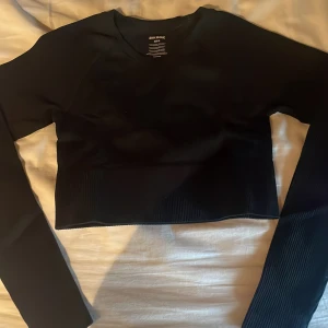 Svart ribbad croppad topp Bik Bok - Svart långärmad croppad topp från Bik Bok i ribbat material. Snygg och enkel modell med rund halsringning och tight passform. Väldigt bra skick.