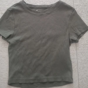 GRÖN T-SHIRT Strl S - Grön t-shirt, kort modell. Använd men bra skick. Storlek S. Söm släppt lite bak, VG se bild, inget som påverkar funktionen. 