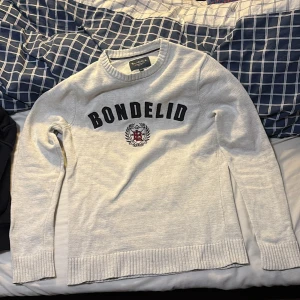 Vit sweatshirt från Bondelid - Säljer en stilren beige tröja från Bondelid med broderad logga i svart och rött på tröjan. Den är i storlek s och har väldigt bra passform, sitter bra på dig runt 180 cm. Pris kan diskuteras vid snabb affär. 