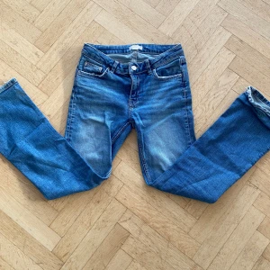 Blå bootcut jeans  - Snygga blå jeans från Gina tricot med klassisk femficksdesign och knappgylf. De har en avslappnad passform och är perfekta för en casual look. Byxorna har en lätt tvättad färg och är ganska lågmidjade. 