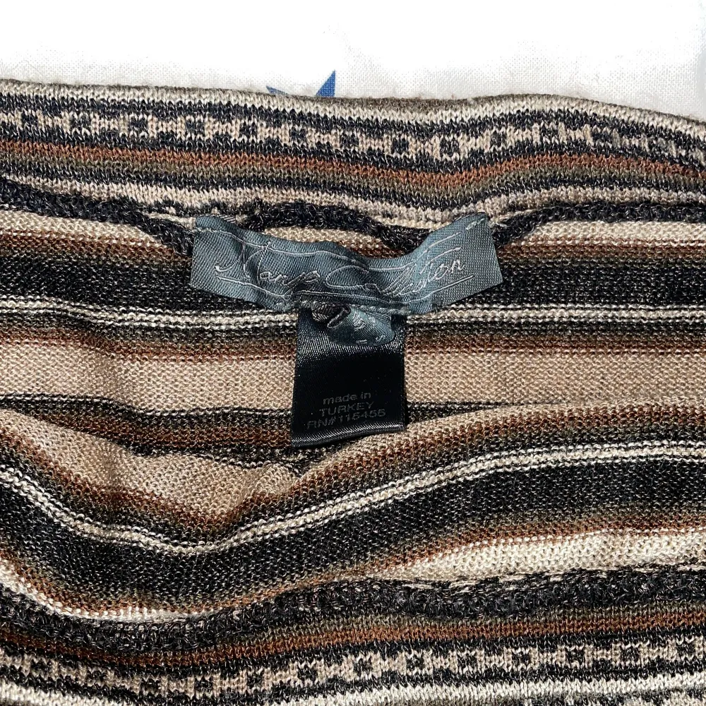 Snygg randig kjol från Laura Clement i jordnära toner som brunt, beige och svart. Kjolen har ett dekorativt bälte i midjan och är perfekt för en stilren look. Tillverkad i Turkiet.. Hameet.