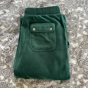 mörkgröna juicy byxor - Säljer ett par supersnygga och jätte bekväma mörkgröna juicy couture byxor. använda och tvättade några gånger vilket man ser på bilderna. strl 15-16 år men sitter som S/M. köpte nya för 800kr. skriv gärna vid frågor🩷pris kan diskuteras